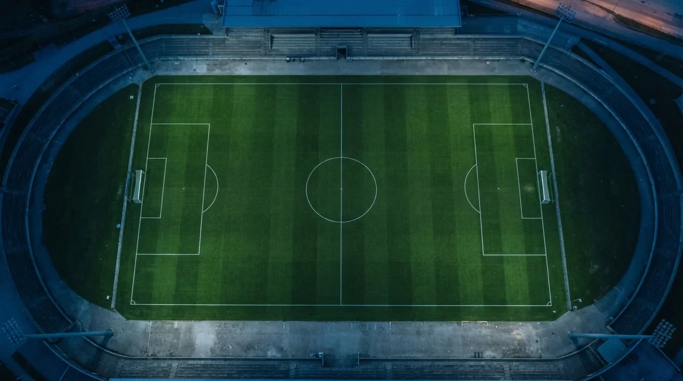 Ein Fußballplatz am Abend aus der Vogelperspektive, Flutlichtmasten ausgeschaltet, die Rasenlinien deutlich sichtbar.