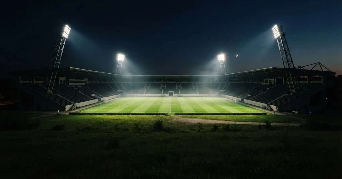 Ein Stadion bei Nacht unter Flutlicht aus der Ferne gesehen, der Rasen ist hell erleuchtet, keine erkennbaren Personen.